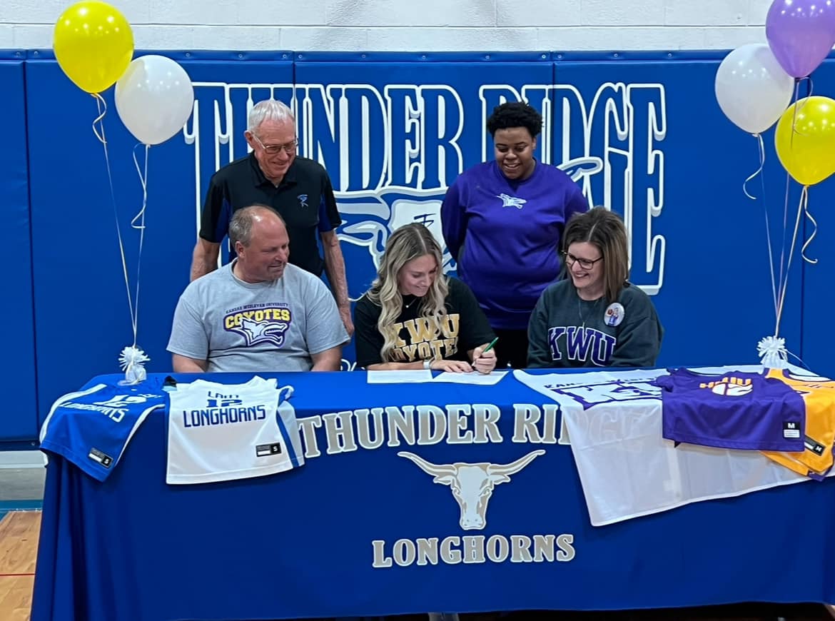 Pictured: Front row (L to R): Father Ryan Rietzke, Kamryn Rietzke, Mother Tiffany Rietzke; Back row (L to R): Thunder Ridge AD Don Wiens, KWU Assistant Coach Lauren Brown.
